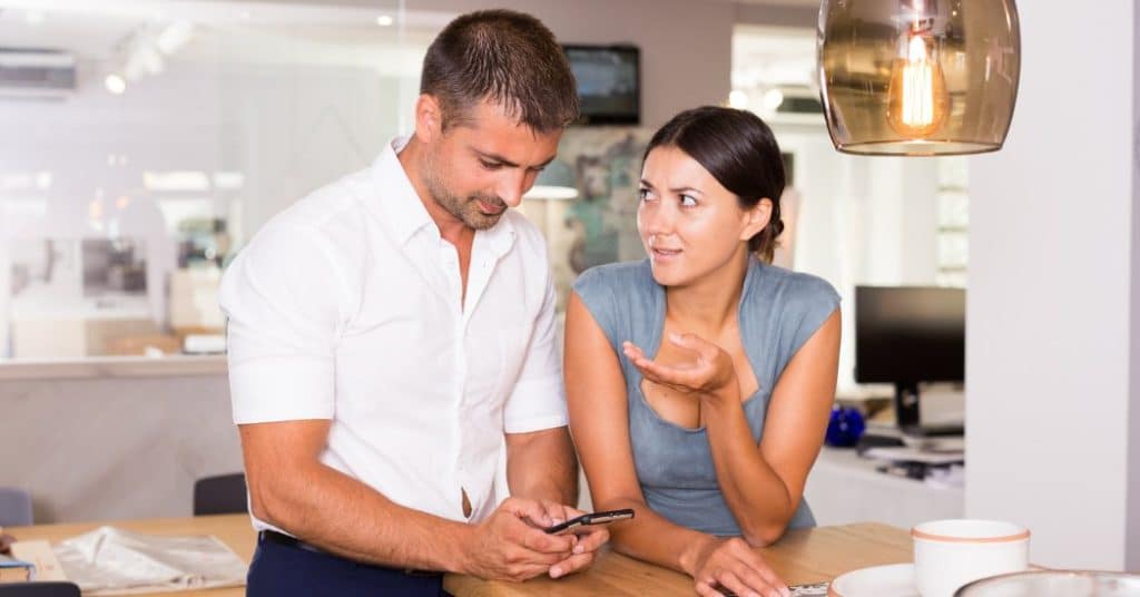 male distracted by phone while female is talking