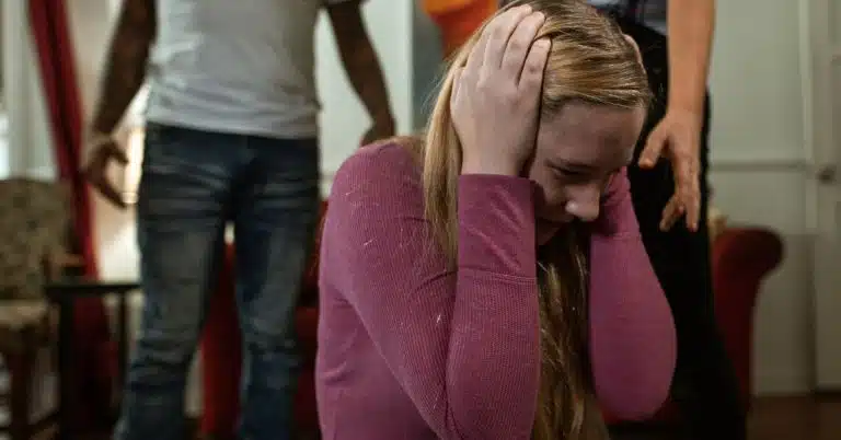 girl holding her head while parents fight